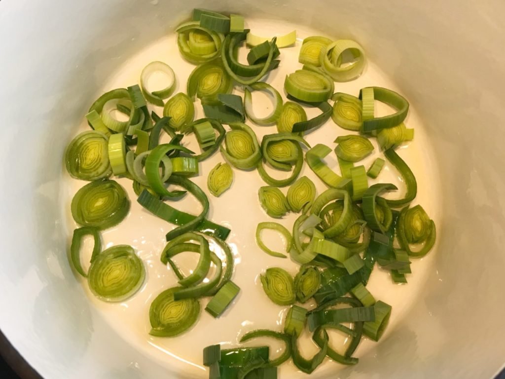 Leek being sauteed in olive oil in dutch oven