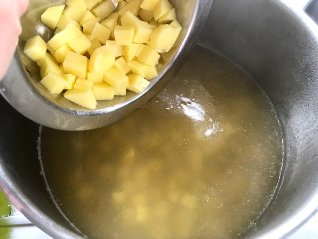 Adding potatoes to soup pot