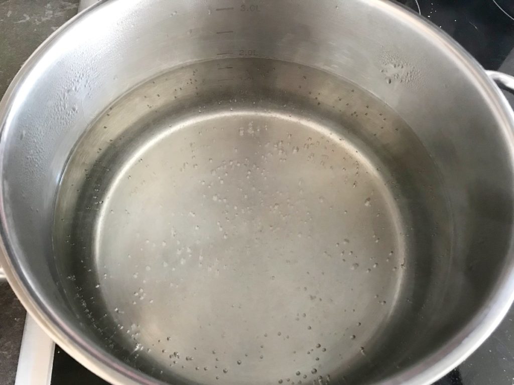 Water coming to a boil in stainless steel pot.