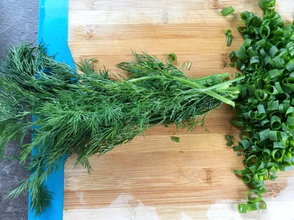 Dill and green onion on cutting board