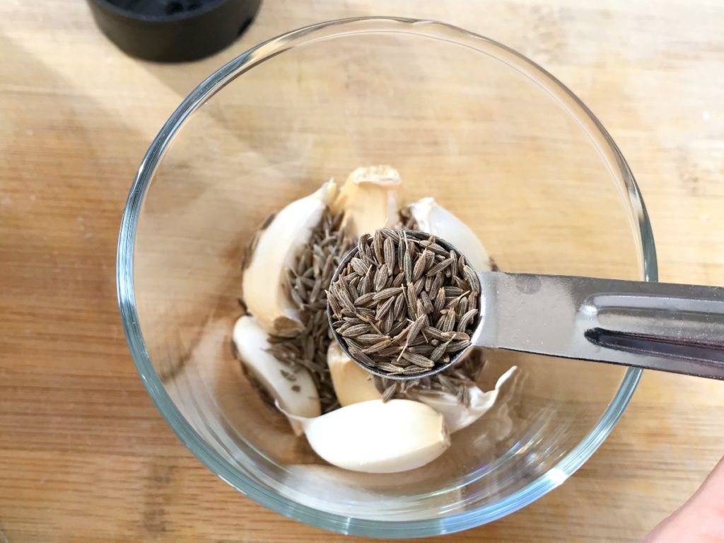 Cumin added to garlic in bowl