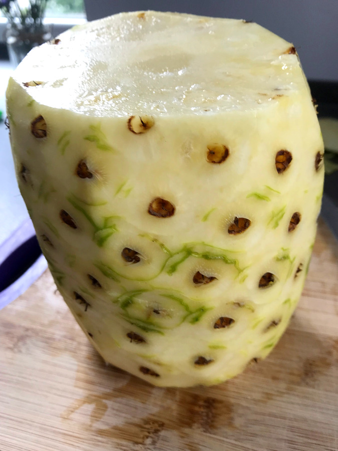 Pineapple on cutting board with rind cut off