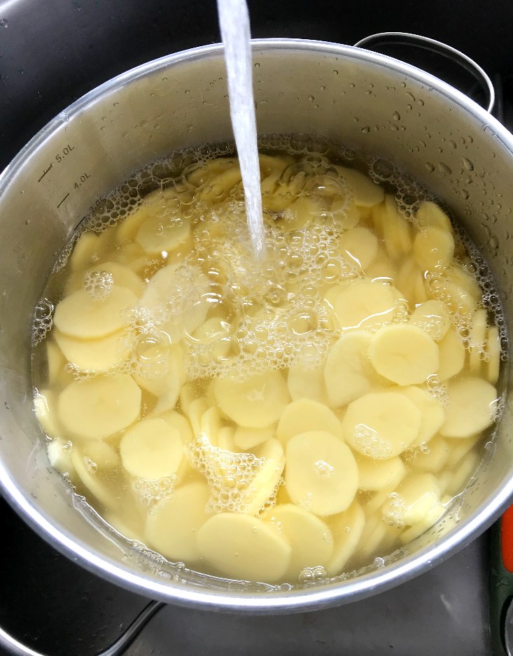 Sliced potatoes in a pot covered with water