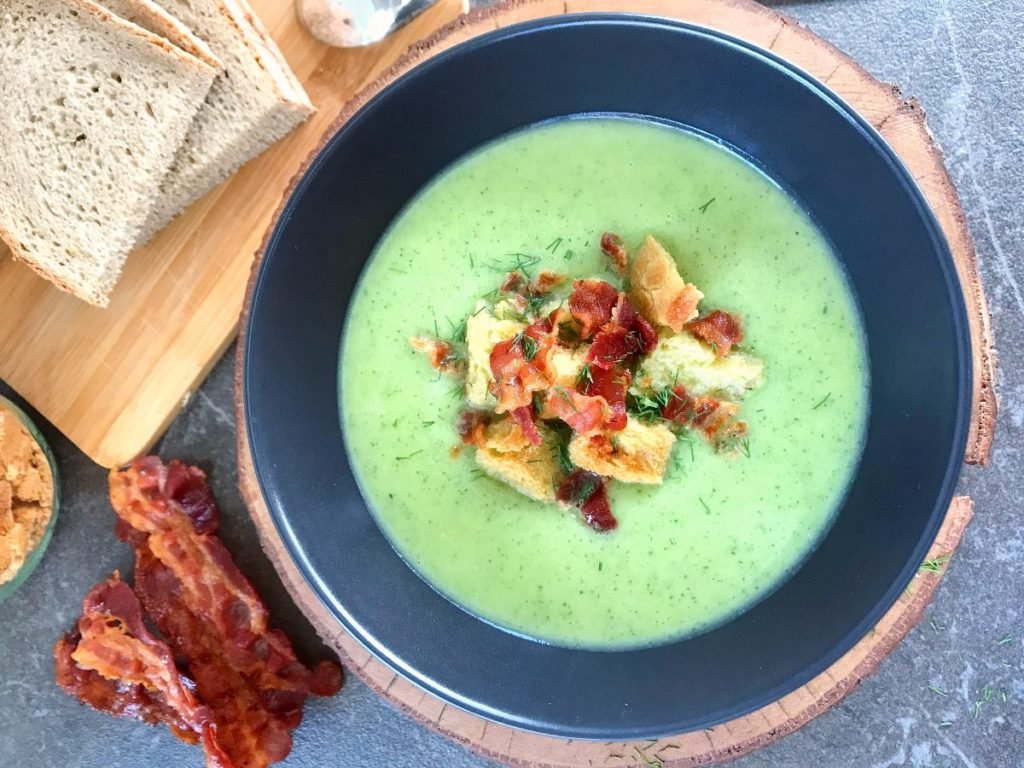 Zucchini served in bowl with croutons and bacon.