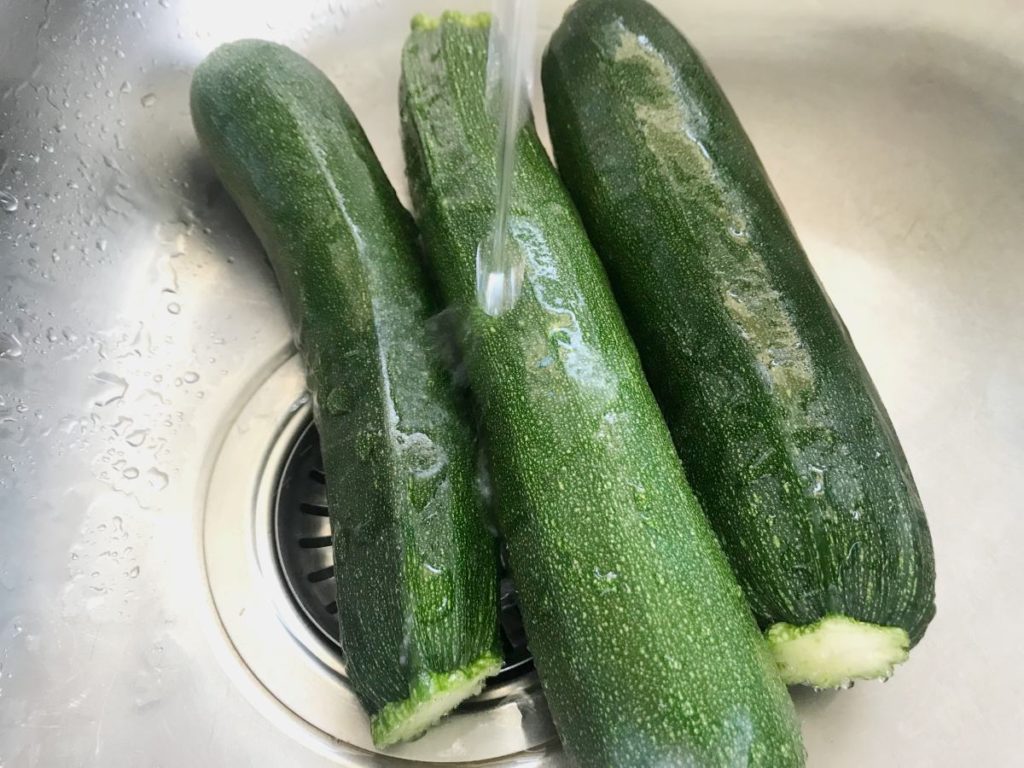 Zucchini in sink washed with water
