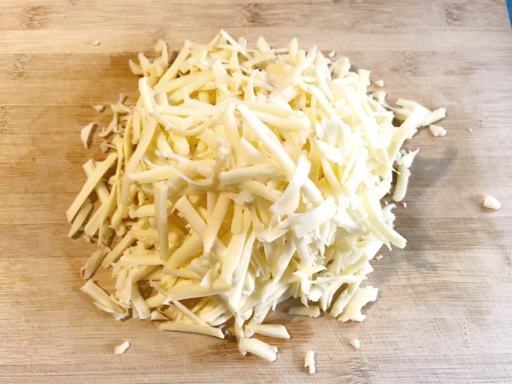 Shredded cheese on a bamboo board.