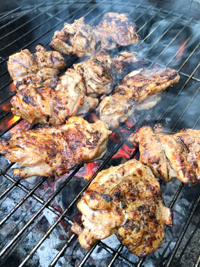 Tender grilled chicken thighs grilled on a grill using charcoal