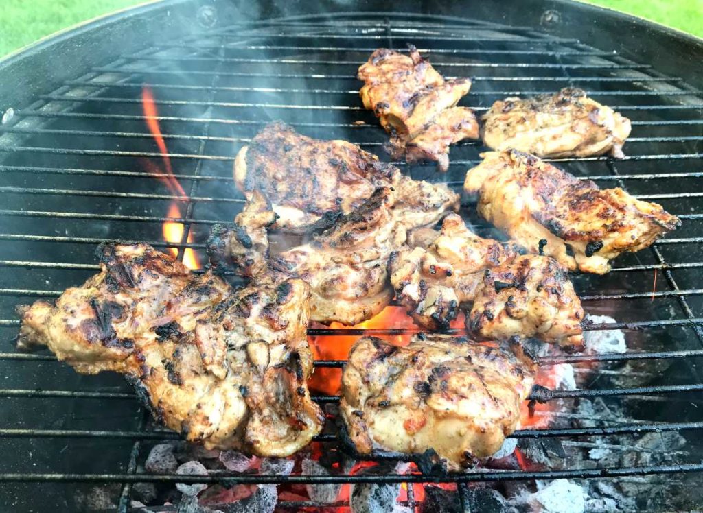 Tender chicken thighs being grilled on a grill.