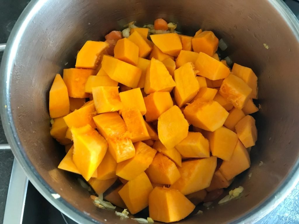 Chopped red kuri squash added to the soup pot.