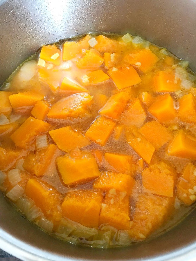 Cooked red kuri and veggies in a soup pot.