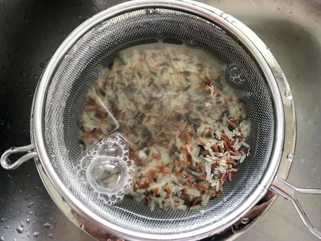 Wild rice washed in a sieve.
