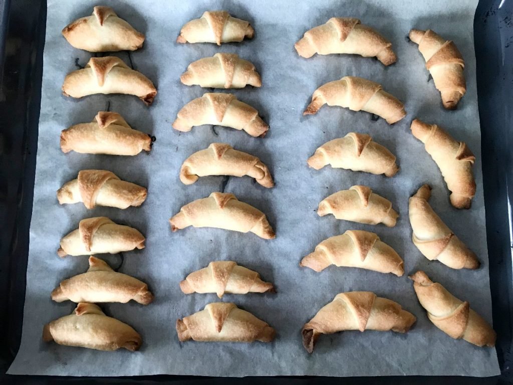 Baked rugelach cookies on a baking sheet.