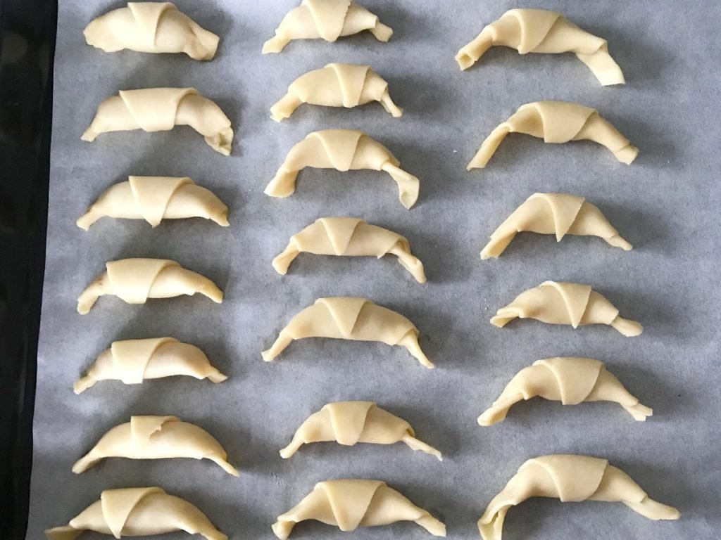 Rugelach twists on a baking sheet lined with parchment paper.