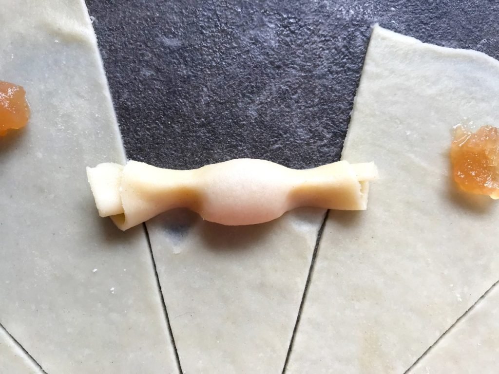 Dough being rolled up into a rugelach crescent cookie.