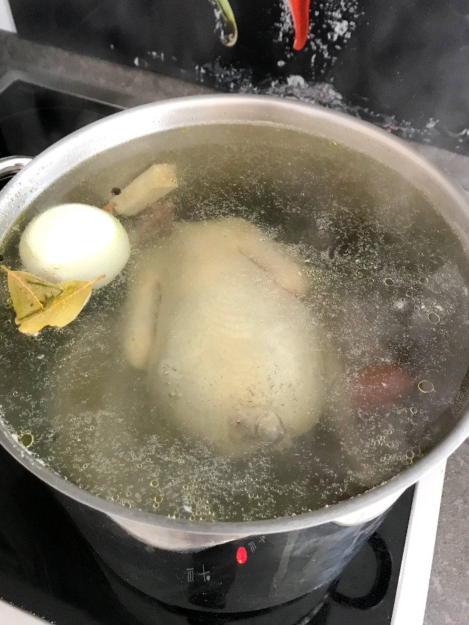 Chicken stock cooking in stock pot.