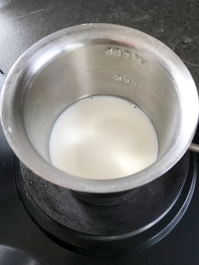 Milk heating up in a small saucepan.