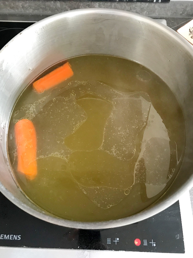 Cooked chicken broth in stock pot.