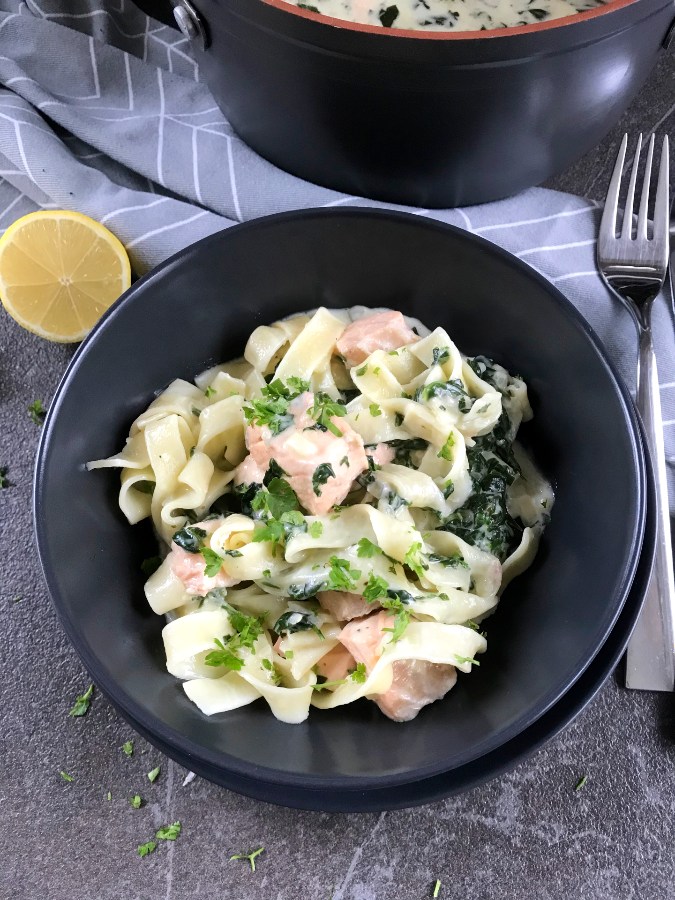 Salmon Spinach pasta served in gray plate.
