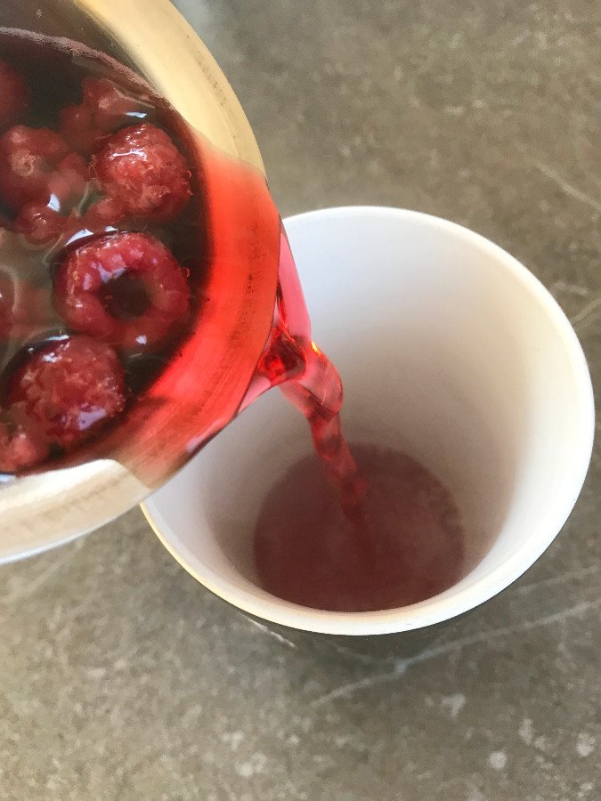 Raspberry tea poured into a serving mug.