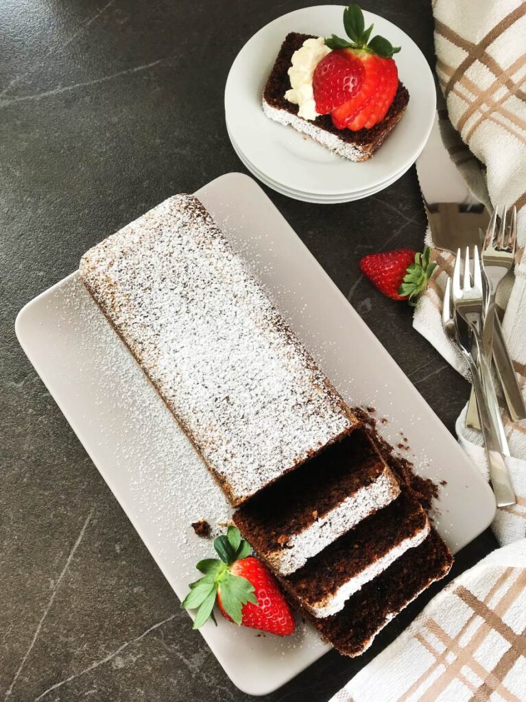 German Hot Chocolate cake served on a platter with strawberries utensils and kitchen towel on the side.