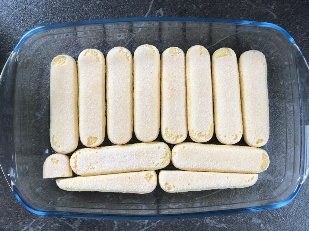 Ladyfinger cookies laid out in a casserole dish