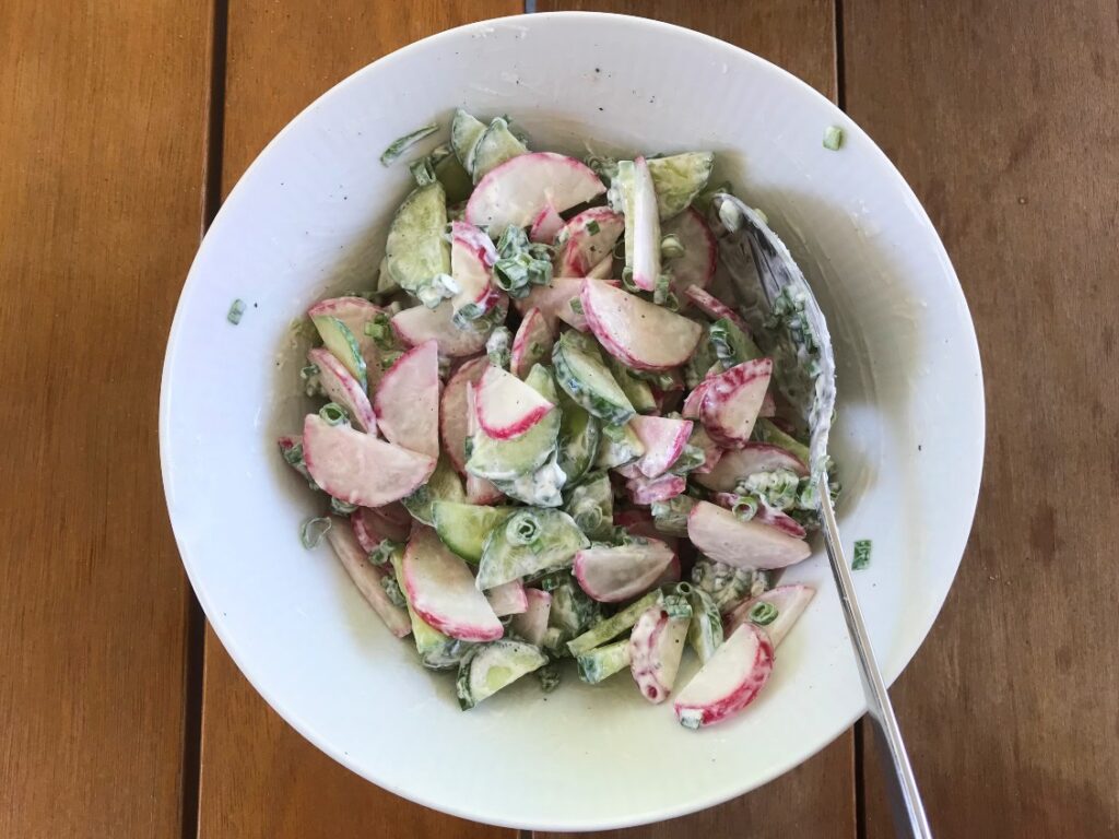 Radish cucumber salad mixed together in a white salad bowl.
