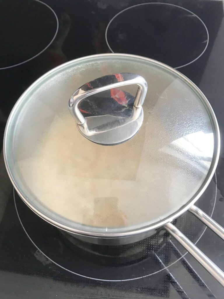 Cooked oatmeal resting in a small saucepan with the lid on.
