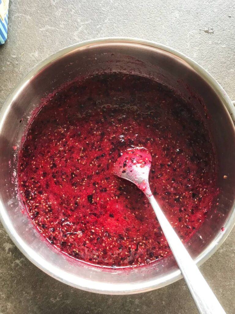 Sugar and ground black currant berries mixed in a pot.