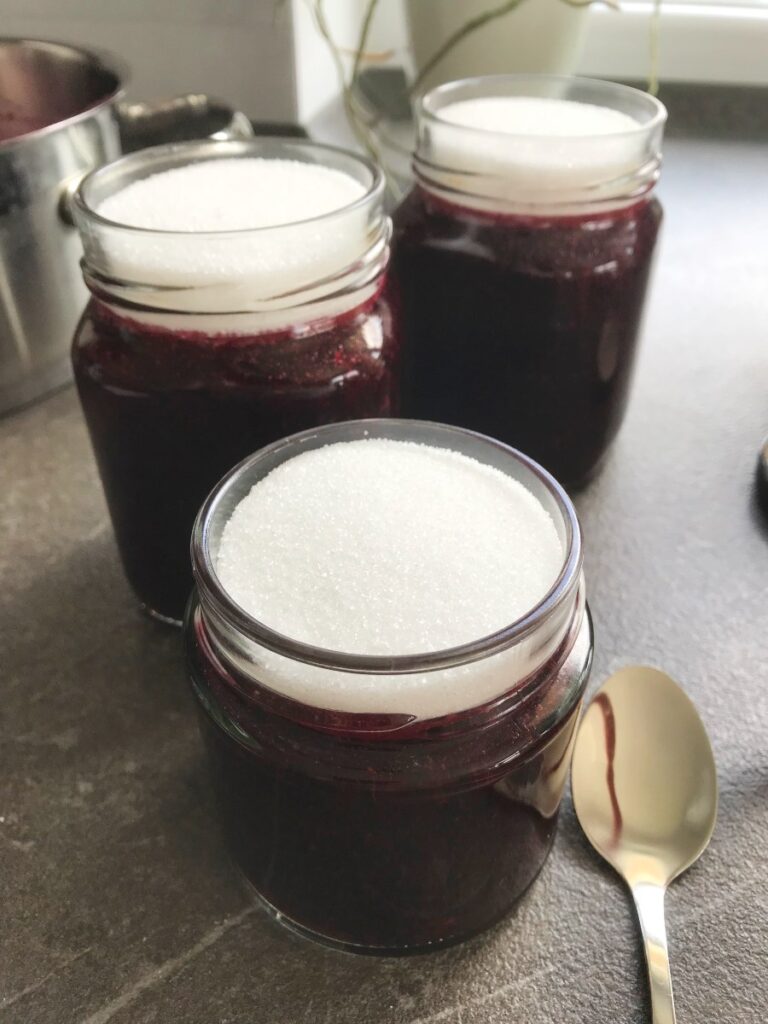 Three black currant jars with sugar layer seals.