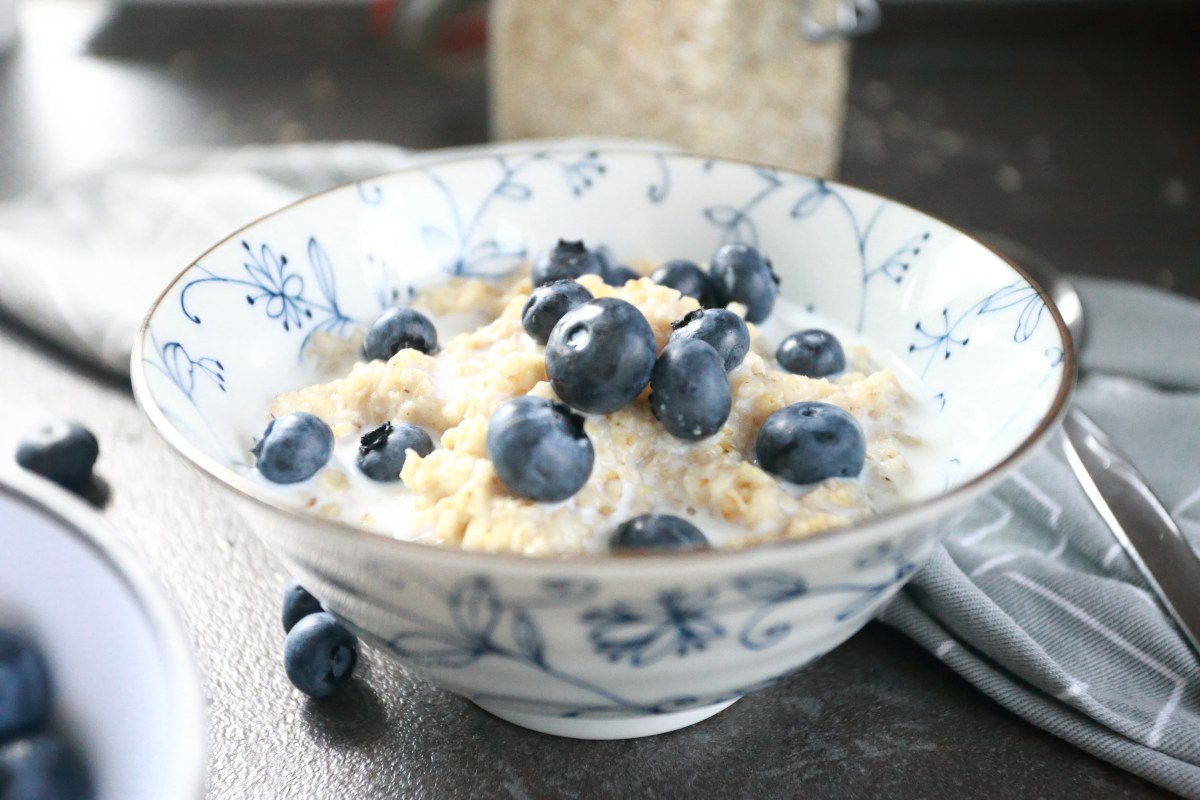 Oatmeal porridge served in a bowl with milk and blueberries.