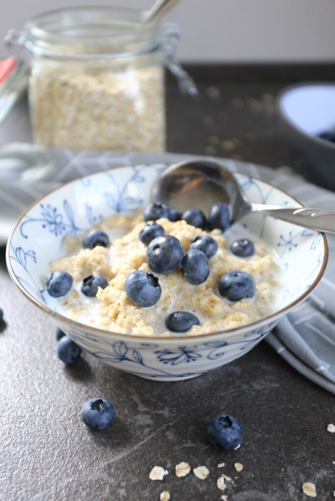 Oatmeal porridge served in bowl with blueberries.