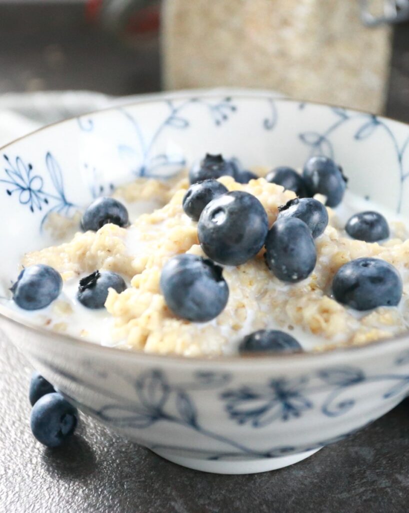 Oatmeal porridge served in a bowl with blueberries and milk.