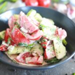 Creamy Cucumber Tomato Salad served in a charcoal colored bowl.