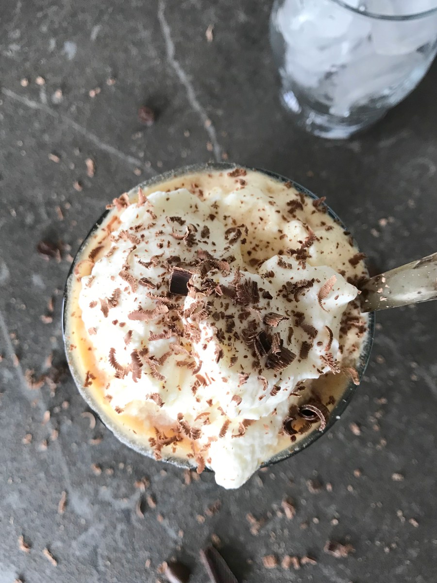 Iced coffee in a glass with whipped cream and chocolate shavings ready for iced coffee tasting.