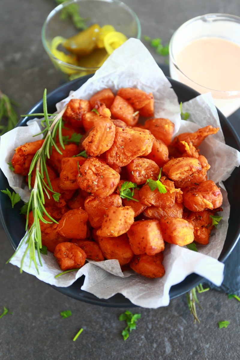 Sweet potato cubes served in a bowl with pickles and mayo ketchup sauce on the side.