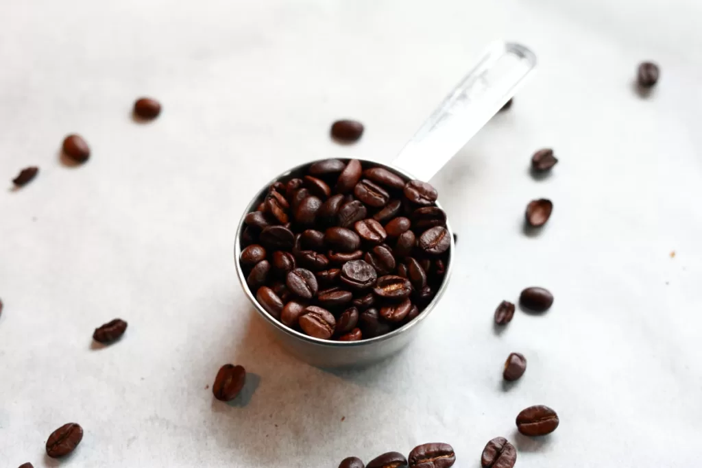 Coffee beans in a stainless steel measuring cup.