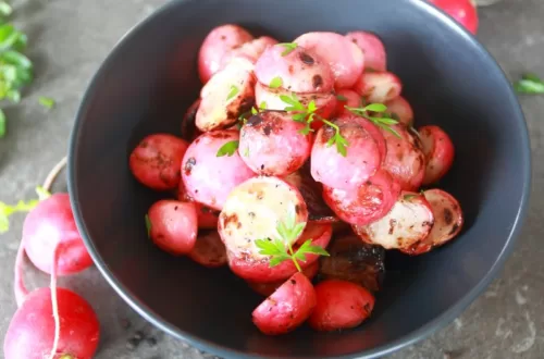 Grilled radishes in a bowl surrounded by fresh radishes and black pepper corns.