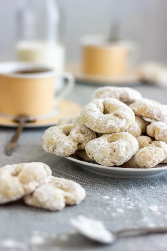Spanish white wine cookies on a plate with a cup of coffee in the background.