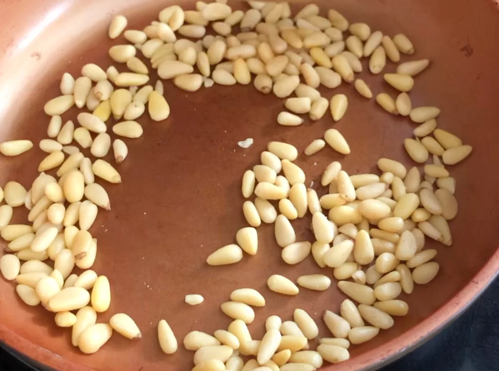 Pine nuts roasting in a skillet.
