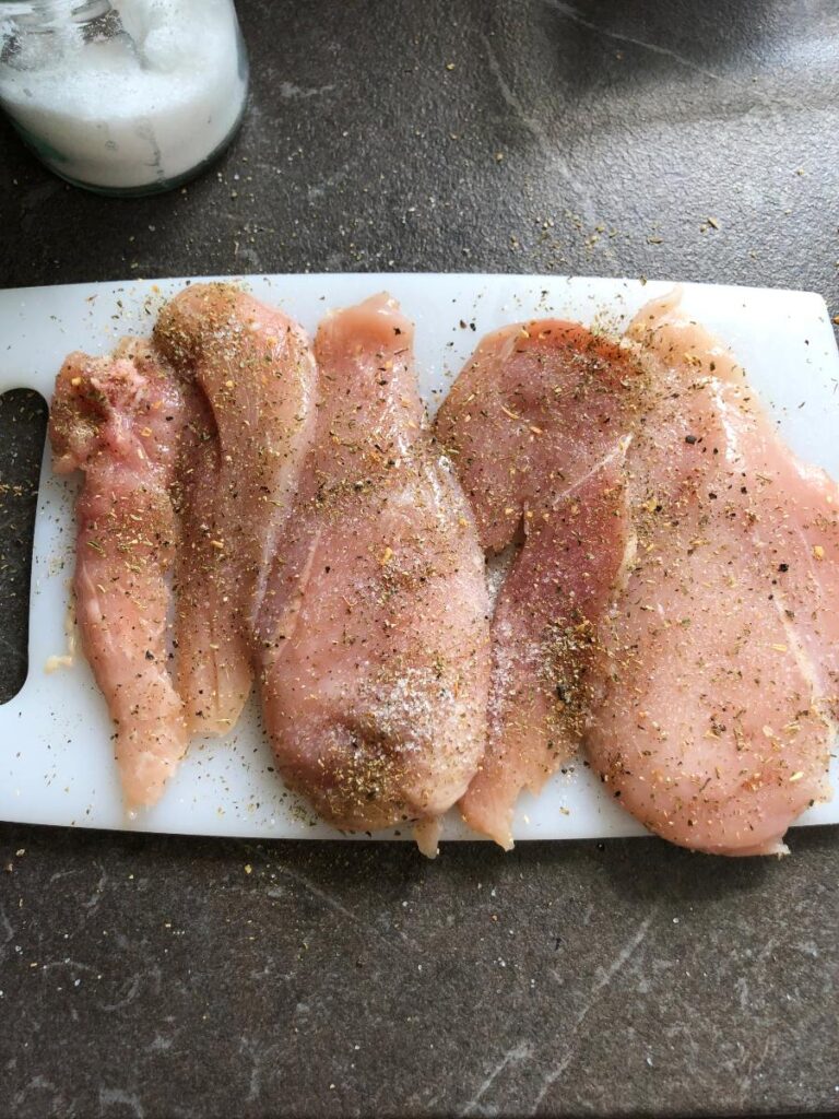 Seasoned chicken breast halves on a cutting board