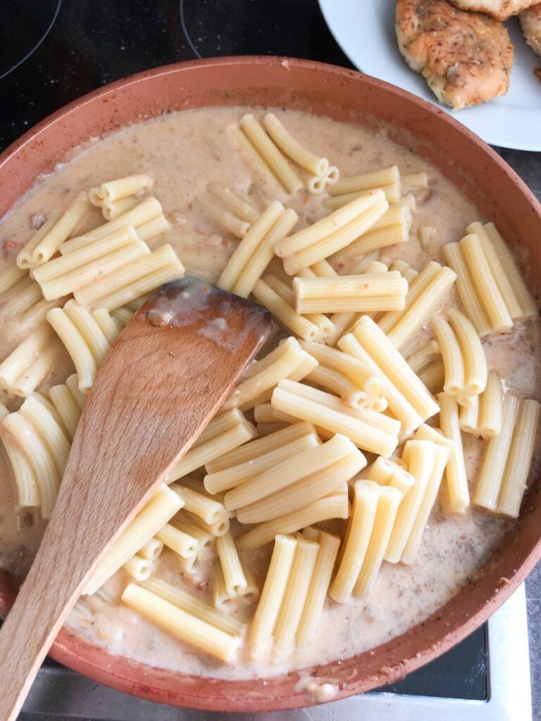 Trigatelli pasta added to sauce in a skillet.