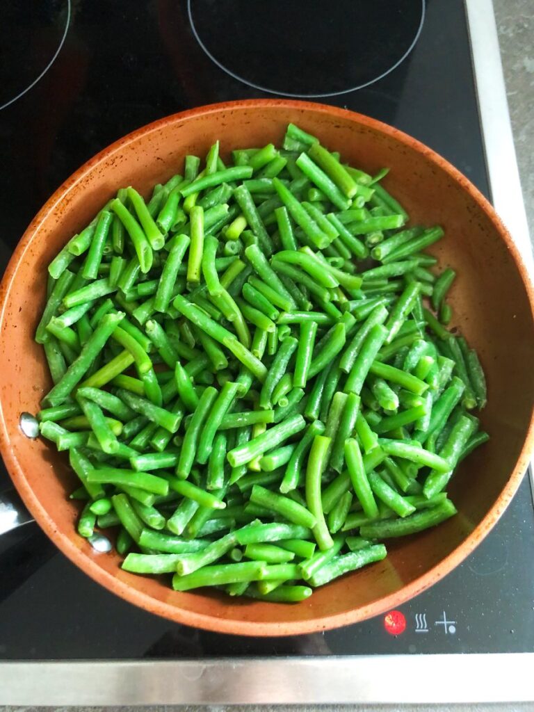 Green beans sautéing in a skillet