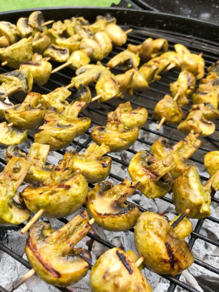 Mushrooms grilling on skewers on a charcoal grill