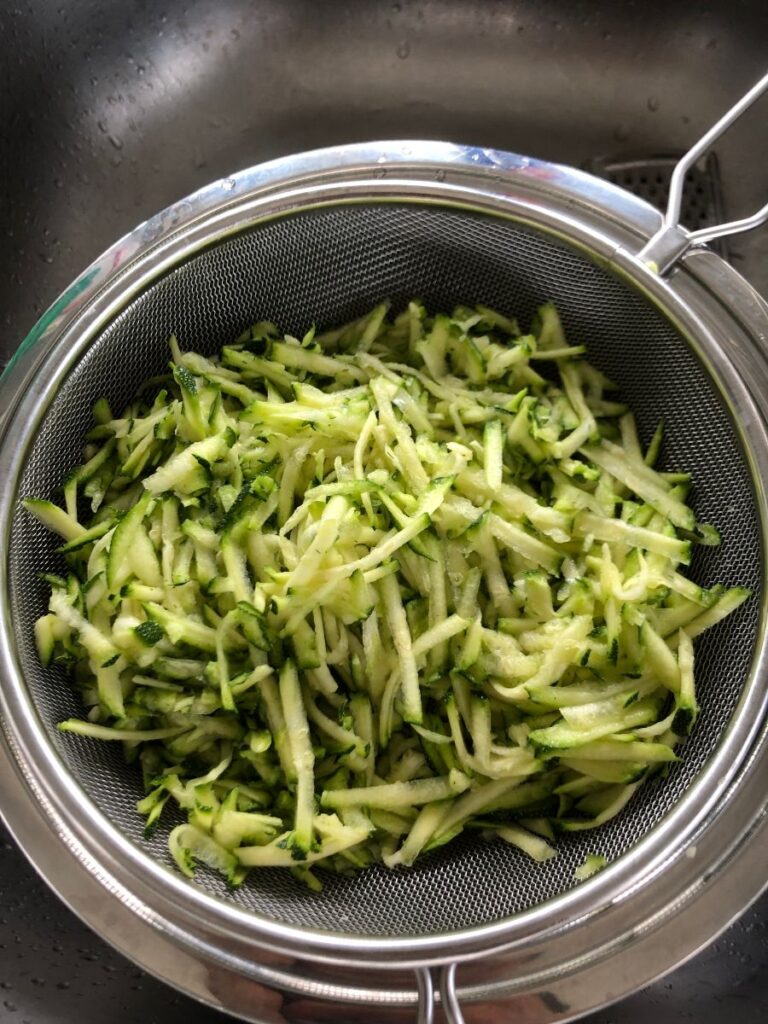 shredded zucchini in a sieve.