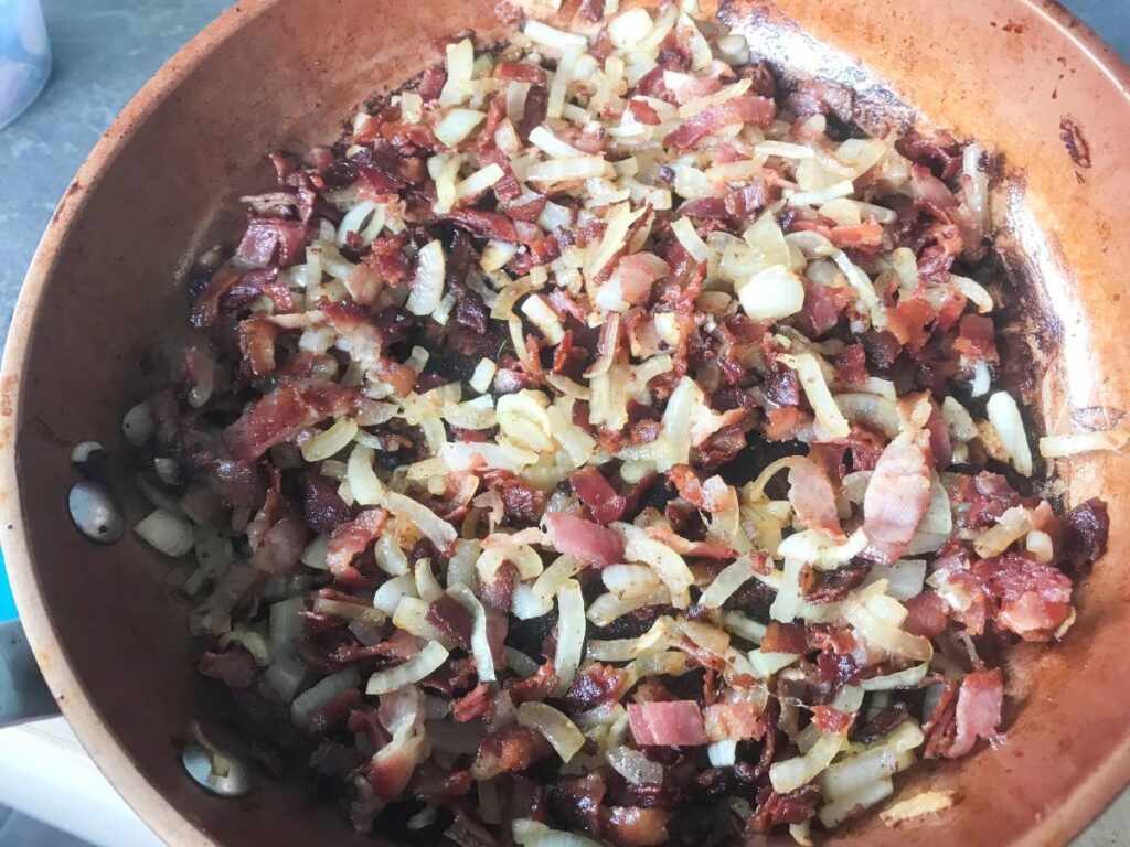 Bacon and Onion sauteed in a skillet.