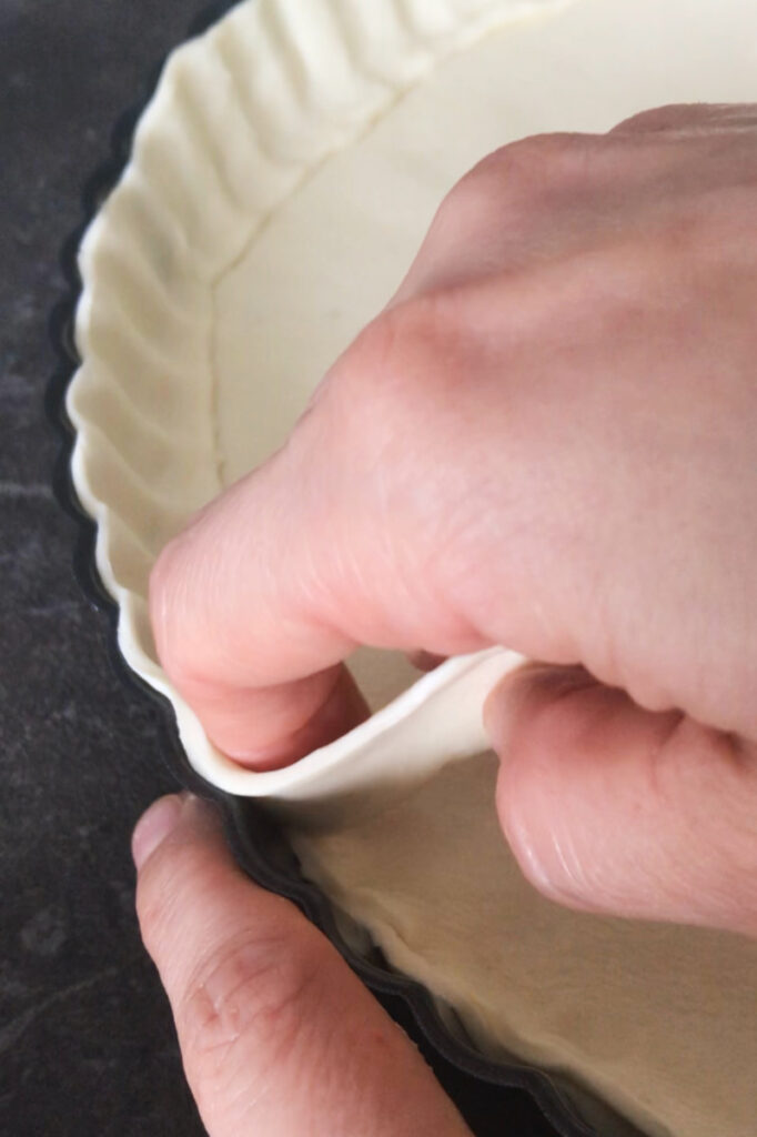 Puff pastry dough placed on edges of tart pan