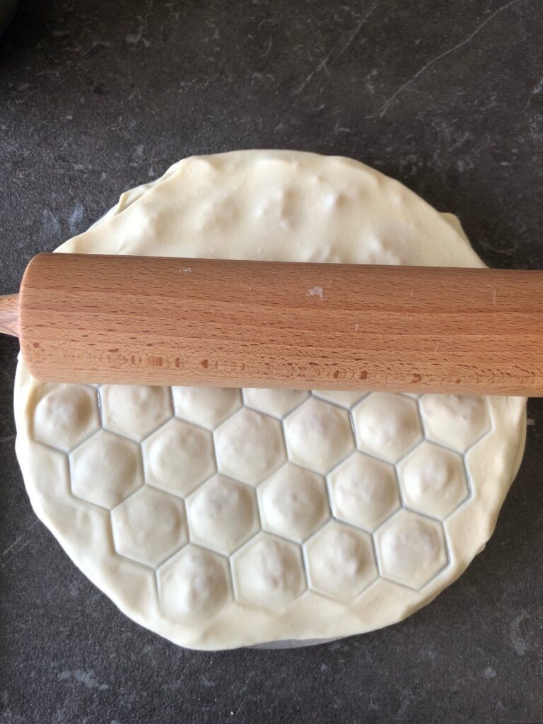 rolling pin being rolled over pelmenitsa