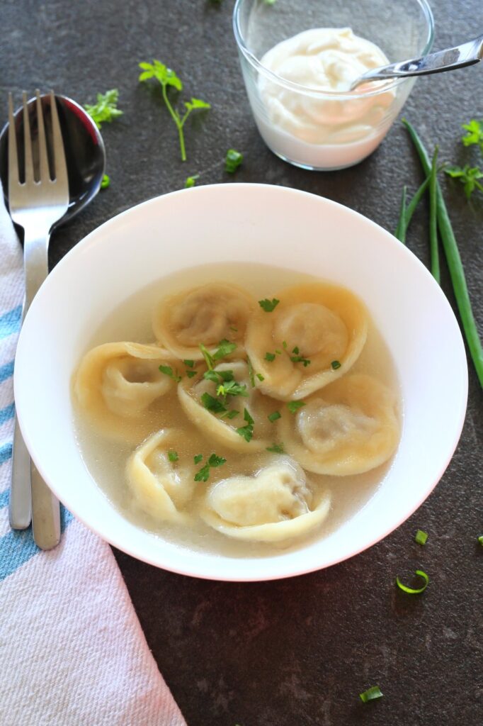 Pelmeni meat dumplings served with broth in a bowl