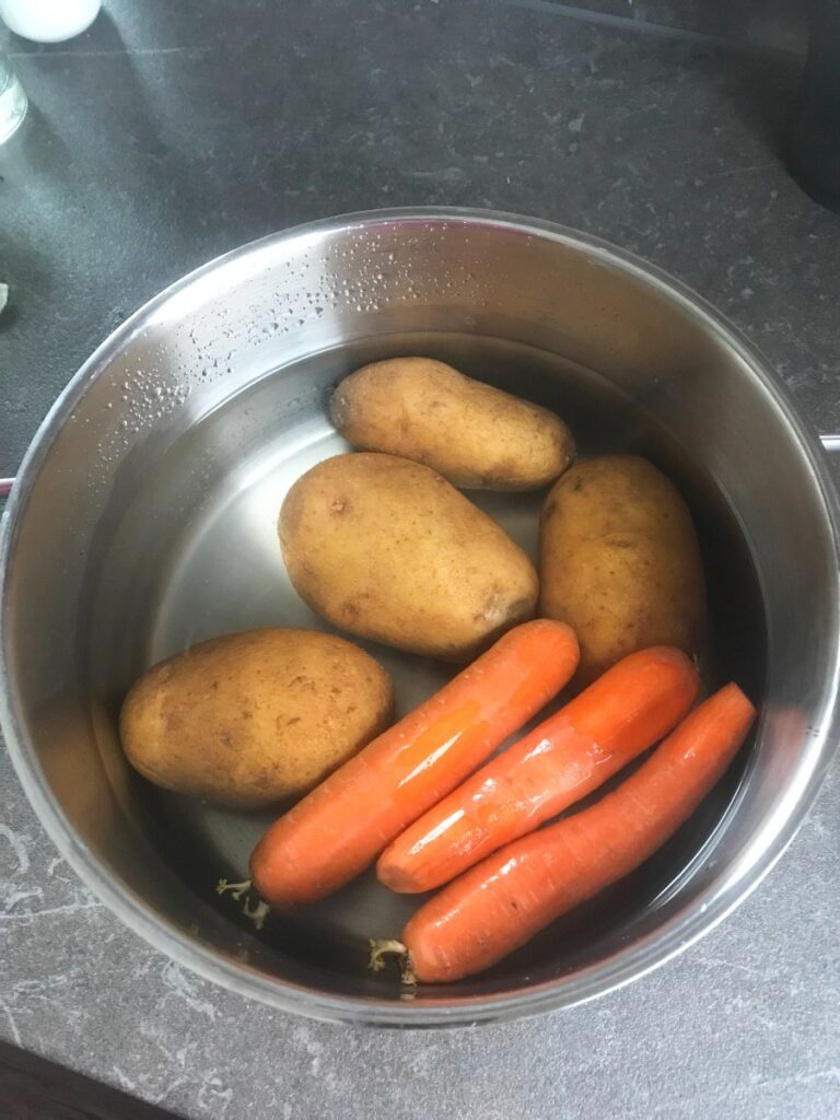 Potatoes and carrots cooked in a pot.