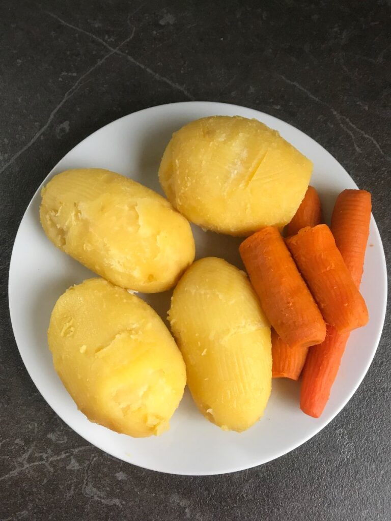 Cooked and peeled potatoes and carrots on a plate